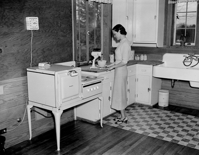 A housewife is shown as she prepares a meal in her all-electric kitchen in Morris, Tenn.