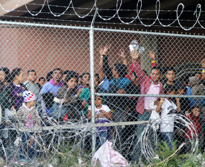 Migrant families wait behind razor wire in a Texas detention camp