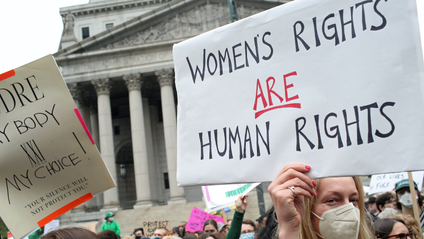 protestors outside the US Supreme Court holding a sign that says &quot;Women&#039;s rights are human rights&quot;