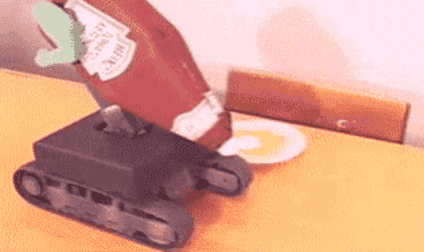 A bottle of Ketchup is attached to a mini motorized tank, and it&#039;s doing a poor job of squirting the condiment on a burger.