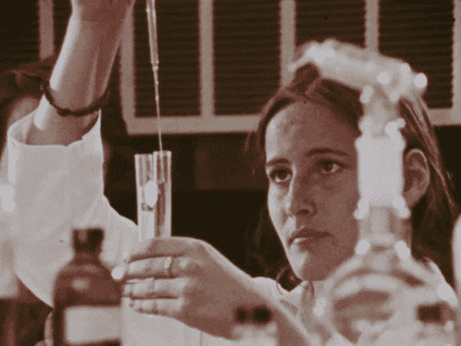 A woman uses a syringe to put liquid in a test tube.