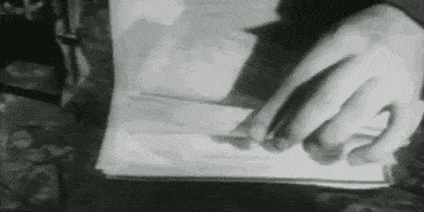 An animated gif showing two hands leafing through a stack of papers and stamping the top corner of some of them.