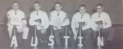 Male cheerleaders pose on one knee with megaphones spelling A-U-S-T-I-N.