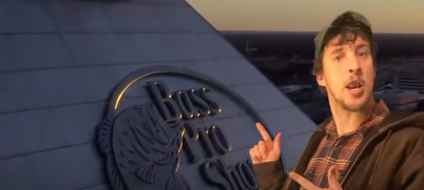 A screenshot from YouTube of a man wearing a baseball cap pointing to a pyramid in the background that says Bass Pro Shops.