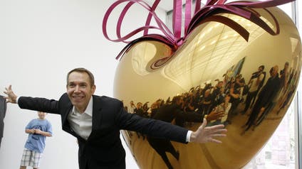 Media takes pictures as U.S.artist Jeff Koons poses in front of his sculpture 'Hanging Heart (Gold/Magenta)' from 1994-2006 during a media preview of his exhibition at the Fondation Beyeler in the Swiss town of Riehen near Basel May 11, 2012. The exhibition 'Jeff Koons' is opened to the public from May 13 to September 2.