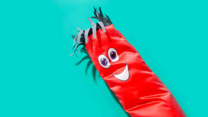 a red inflatable tube man with two eyes and a smiling mouth as well as some fringe hair