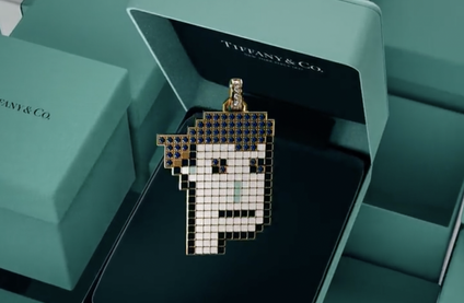 An image of an open Tiffany & Co box in the classic blue bird eggshell shade, the interior is black and features a pendant of a stylized, pixelated person's face made out of gems.