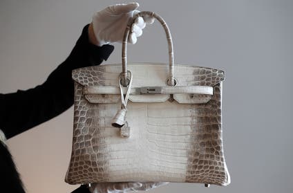 A staff member poses holding a rare Hermes handbag, the mat white Birkin Himalaya 35 during an auction preview at Christie's in Paris, France, March 4, 2016. REUTERS/Christian Hartmann - RTS9B2I