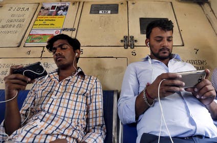 Commuters watch videos on their mobile phones as they travel in a suburban train in Mumbai, India, April 2, 2016. With smartphone sales booming and India preparing for nationwide 4G Internet access, India's film and TV industry hopes the ease of tapping your phone for the latest release will generate profits at last, overcoming the problems of woefully few cinemas and rampant piracy. Picture taken April 2, 2016.
