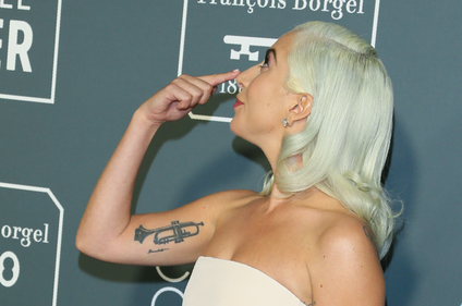 Lady Gaga points to her nose.