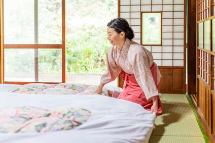 A photograph of a Japanese woman making a traditional futon bed