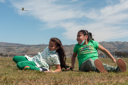 An airplane flies overhead as students at Donald J. Meyer Elementary School play outside.