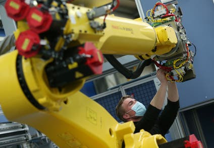 An employee works on an industrial robot at HAHN Automation company in Rheinboellen, Germany.