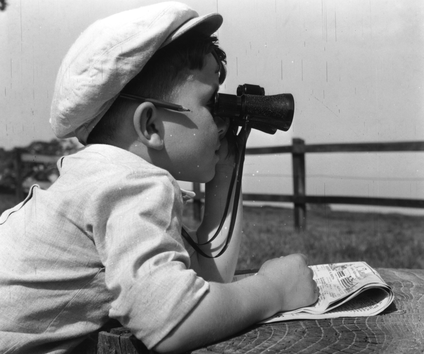 A small child looks through a pair of binoculars. 