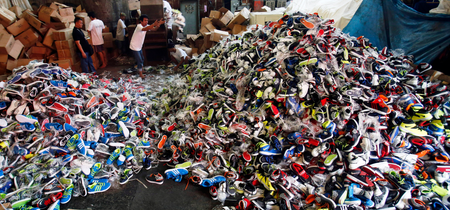 Government workers from the Bureau of Customs destroy counterfeit footwear products in Manila February 24, 2015. A government statement said over 150,000 pairs of fake shoes and slippers of various brands including Nike, Adidas, Converse, Sketchers, North Face, Leaveland, Merrell, Lacoste, Vans, Havaianas and Ipanema worth PHP 50 million ($1.13 million), which were smuggled from China, were destroyed at a government warehouse in Manila on Tuesday.