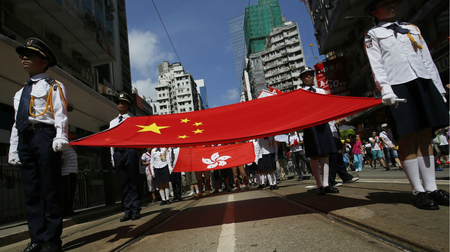 Participants hold a Chinese national flag and a Hong Kong flag as tens of thousands of people march on a down town street to oppose a planned civil disobedience campaign by pro-democracy activists in Hong Kong, Sunday, Aug. 17, 2014. The rally was organized by a pro-Beijing group. Many carried banners or shouted slogans saying they were opposed to the Occupy Central pro-democracy movement