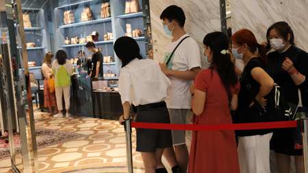 People wearing face masks following the coronavirus disease (COVID-19) outbreak line up outside a Gucci store at the Sanya International Duty-Free Shopping Complex in Sanya, Hainan province, China November 25, 2020. Picture taken November 25, 2020. REUTERS/Tingshu Wang