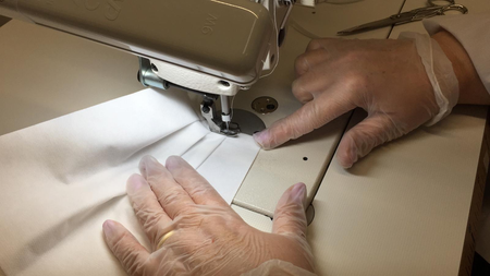 A shot of a worker&#039;s hands sewing a face mask
