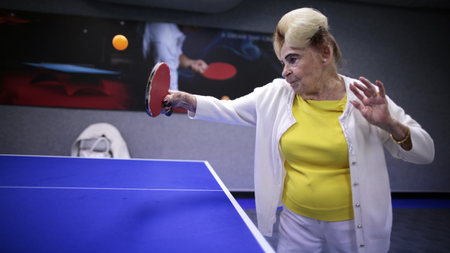 An elderly woman plays pingpong