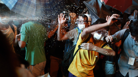 Protesters are pepper sprayed by riot police during a confrontation at Mongkok shopping district in Hong Kong October 17, 2014. Hong Kong riot police used pepper spray and baton charged crowds of pro-democracy protesters on Friday evening as tension escalated after a pre-dawn clearance of a major protest zone in the Chinese-controlled financial hub. REUTERS/Bobby Yip