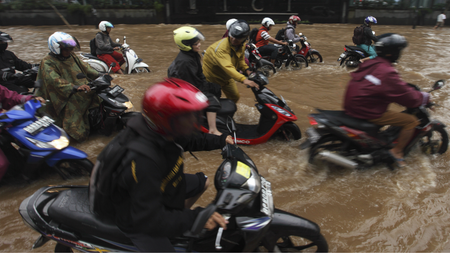 People ride motorcycles through a flooded street in the business district in Jakarta January 18, 2013.