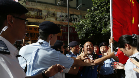 Police stop a pro-China protester carrying a Chinese flag as he tried to approach anti-Chinese demonstrators during a rally near Hong Kong&#039;s Victoria Park on June 4.