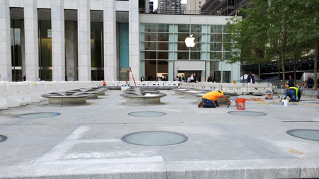 Workers cementing metallic objects onto the ground outside the new Apple Store