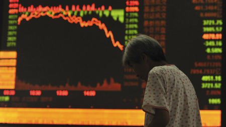 An investor stands in front of an electronic board showing stock information at a brokerage in Fuyang, Anhui province.