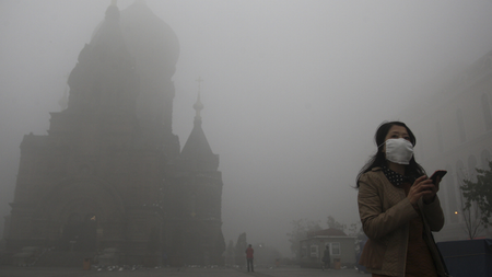 A woman wearing a mask checks her mobile phone during a smoggy day on the square in front of Harbin&#039;s landmark San Sophia church, in Heilongjiang province October 21, 2013. The second day of heavy smog with a PM 2.5 index has forced the closure of schools and highways, exceeding 500 micrograms per cubic meter on Monday morning in downtown Harbin, according to Xinhua News Agency. REUTERS/Stringer