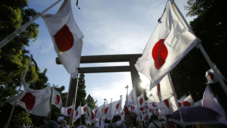 Members of nationalist movement &quot;Ganbare Nippon&quot; holding Japanese national flags gather under the huge Torii gate at the Yasukuni shrine while paying tribute to the war dead in Tokyo August 15, 2014,