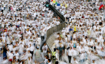 A policeman (bottom centre) looks on as demonstrators march on a main street in Hong Kong during a pro-democracy march July 1, 2004 on the seventh anniversary of the territory&#039;s handover to China. Waving green and black banners and sheltering under umbrellas from the searing sun, protesters chanting &quot;Return power to the people, fight for democracy&quot; streamed from a park to government offices in the heart of the city several kilometres away. Movement in the picture is caused by the slow shutter speed. REUTERS/Bobby Yip BY/FA - RTR5ND5