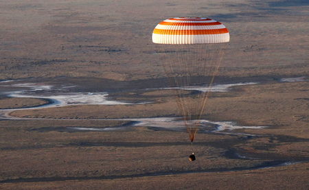 The Soyuz TMA-20M spacecraft capsule carrying International Space Station (ISS) crew descends beneath a parachute near the town of Zhezkazgan (Dzhezkazgan), Kazakhstan