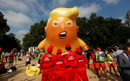 Demonstrators stand in front of a blimp portraying U.S. President Donald Trump, in Parliament Square, during the visit by Trump and First Lady Melania Trump in London