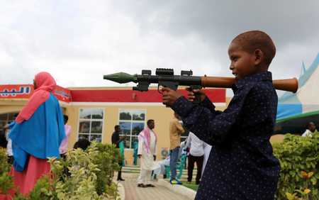 A Somali boy plays with a toy model of a rocket-propelled grenade (RPG) after attending Eid al-Fitr prayers to mark the end of the fasting month of Ramadan in Somalia&#039;s capital Mogadishu, July 6, 2016.