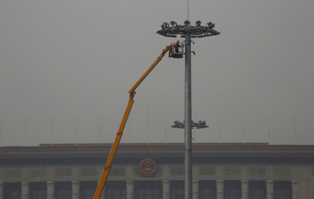 A worker maintains a street light at Tiananmen Square among smog during a polluted day in Beijing on Jan. 6, 2017.