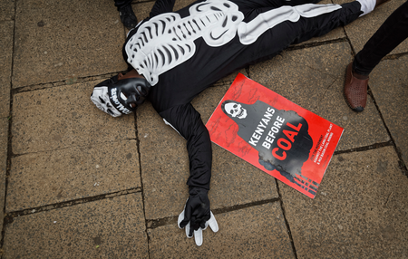 An environmental protester lies on the ground as he demonstrates against recent government plans to mine coal and open a coal-fired power plant, in downtown Nairobi, Kenya Tuesday, June 5, 2018. Kenyan activists protested plans for the joint venture between the Kenyan and Chinese governments in Lamu County, saying it will have devastating effect on the environment and health of local populations.