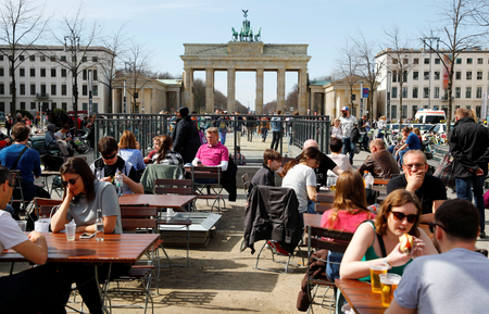 People enjoy sunny weather at the Brandenburg Gate in Berlin