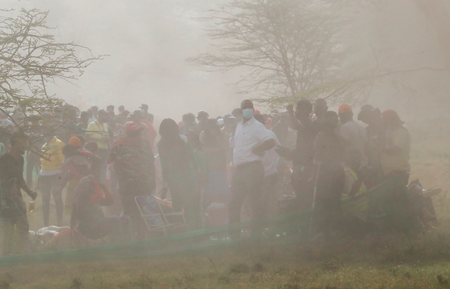 Spectators stand in the dust.
