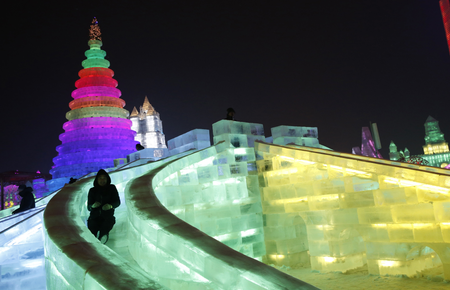 A man rides a slide on an ice sculpture illuminated by coloured lights during a trial operation ahead of the 31st Harbin International Ice and Snow Festival in the northern city of Harbin, Heilongjiang province, January 4, 2015. The winter festival will be officially opened on January 5, 2015. REUTERS/Kim Kyung-Hoon