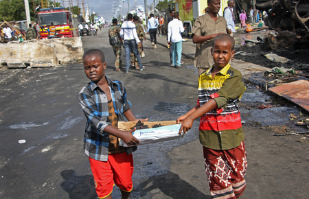 Somali children assist other civilians and security forces in their rescue efforts by carrying away unidentified charred human remains in a cardboard box, to clear the scene of Saturday&#039;s blast, in Mogadishu, Somalia.