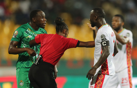 A female referee uses her hands to separate two men from each other at the Africa Cup of Nations 2022