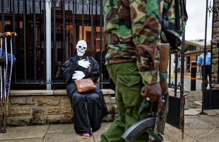 An armed police officer walks past an environmental protester wearing a skeleton costume as she demonstrates outside parliament against recent government plans to mine coal and open a coal-fired power plant, in downtown Nairobi, Kenya Tuesday, June 5, 2018. Kenyan activists protested plans for the joint venture between the Kenyan and Chinese governments in Lamu County, saying it will have devastating effect on the environment and health of local populations.