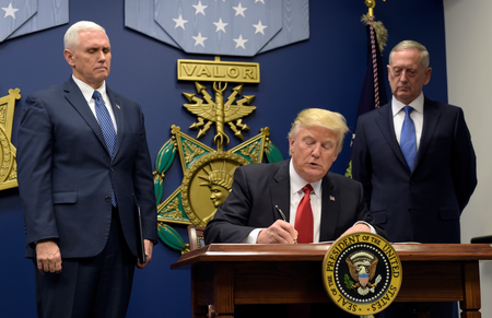 President Donald Trump, center, with Vice President Mike Pence, left, and Defense Secretary James Mattis, right, watching, signs an executive action on extreme vetting at the Pentagon in Washington, Friday, Jan. 27, 2017. (AP Photo/Susan Walsh)