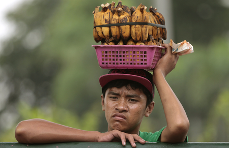 A Filipino boy selling boiled bananas rests on a steel fence in Quezon city, north of Manila, Philippines on Wednesday, Sept. 11, 2013. (AP Photo/Aaron Favila
