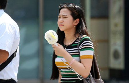 A woman holds a portable fan at a business district in Tokyo, Monday, July 23, 2018. Searing hot temperatures are forecast for wide swaths of Japan and South Korea in a long-running heat wave. The mercury is expected to reach 39 degrees Celsius (102 degrees Fahrenheit) on Monday in the city of Nagoya in central Japan and reach 37 in Tokyo. Deaths have been reported almost every day.