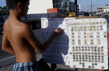 A teenager places bets on a numbers game along a road in San Fernando city, north of Manila.