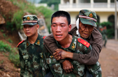 A paramilitary policeman carries an elderly man on his back after an earthquake hit Ludian county of Zhaotong, Yunnan province August 3, 2014. The magnitude 6.5 earthquake struck southwestern China on Sunday, killing at least 150 people in the remote mountainous area of Yunnan province, causing some buildings, including a school, to collapse, Xinhua News Agency reported. REUTERS/China Daily (CHINA - Tags: DISASTER) CHINA OUT. NO COMMERCIAL OR EDITORIAL SALES IN CHINA - RTR412QN