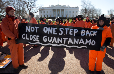 Protesters wearing orange jumpsuits depicting Guantanamo Bay detainees, hold a sign that reads &quot;Not One Step Back Close Guantanamo&quot; participate in a rally outside of the White House in Washington Monday, Jan. 11, 2016, calling for a close of the detention center at the U.S. base at Guantanamo Bay, Cuba.