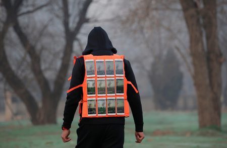 Artist Liu Bolin wearing a vest with 24 mobile phones walks in smog as he live broadcasts air pollution in the city on the fourth day after a red alert was issued for heavy air pollution in Beijing, China, December 19, 2016. REUTERS/Jason Lee - RTX2VLZ9