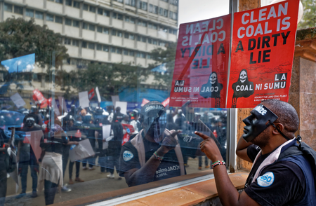 An environmental protester points his finger at the reflective window of the Ministry of Interior, as he demonstrates against recent government plans to mine coal and open a coal-fired power plant, in downtown Nairobi, Kenya Tuesday, June 5, 2018. Kenyan activists protested plans for the joint venture between the Kenyan and Chinese governments in Lamu County, saying it will have devastating effect on the environment and health of local populations.